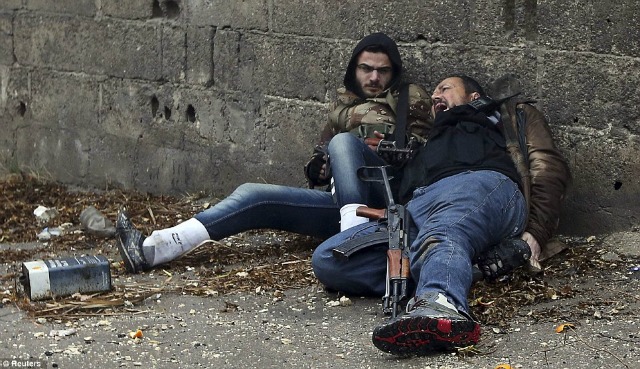 El rebelde herido con su compañero mientras se ocultan detrás de una barda.