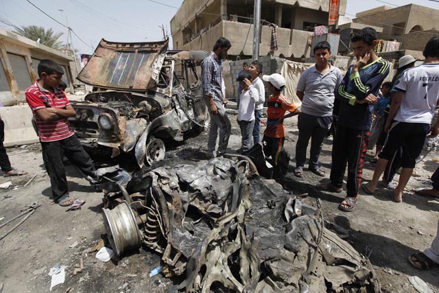 Residents gather at the site of a car bomb attack in the Kamaliya district in Baghdad