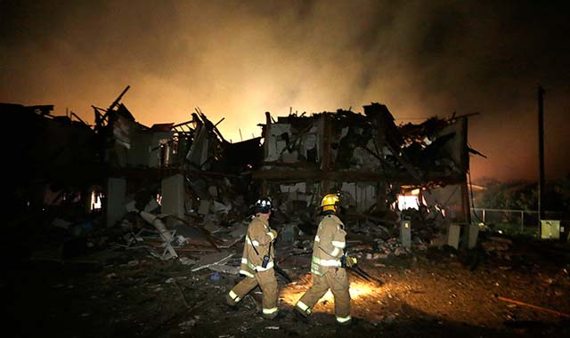 Firefighters check a destroyed apartment complex near the plant
