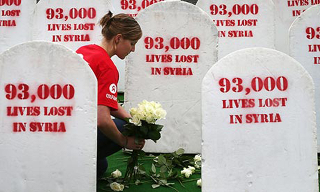 Oxfam worker places roses on gravestones symbolising the 93,000 people killed in Syria's civil war