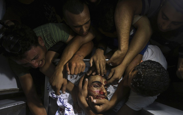 People mourn around the body of a Palestinian militant at a hospital morgue in the central Gaza Strip