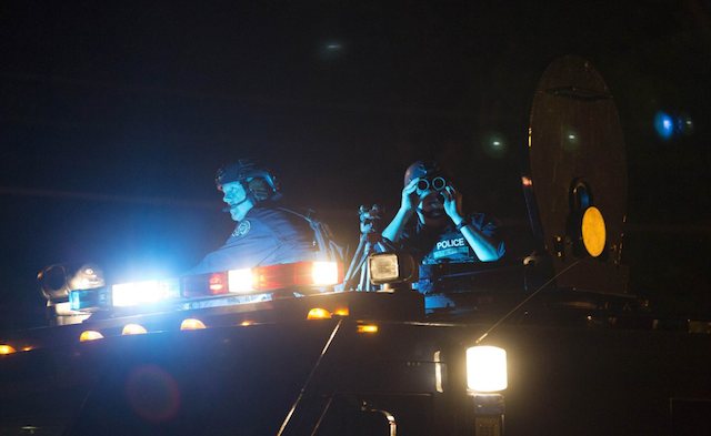 Police officers keep watch from an armored vehicle as they patrol a street in Ferguson