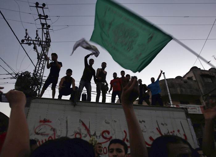 A Palestinian waves a Hamas flag as others celebrate what they said was a victory over Israel, following a ceasefire in Gaza City