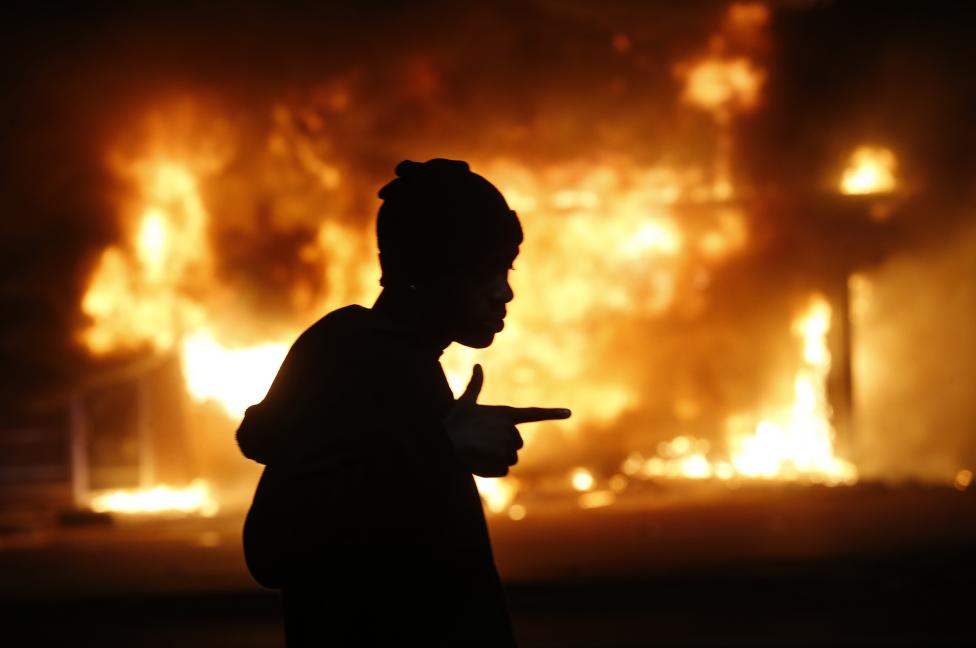A man walks past a burning building during rioting after a grand jury returned no indictment in the shooting of Michael Brown in Ferguson, Missouri