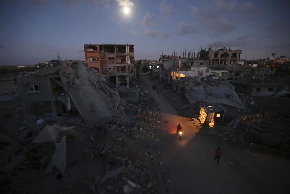 Palestinians commute along a road between ruins of houses, which witnesses said were damaged or destroyed during the Israeli offensive, in Beit Hanoun