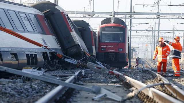 Rescue workers stand next to a derailed train after two trains collided near Rafz
