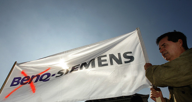 An employee of BenQ's German handset unit holds up a banner during a protest in front of the Siemens headquarter in Munich