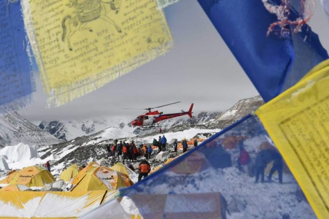 TOPSHOTS Prayer flags frame a rescue helicopter as it ferries the injured from Everest Base Camp on April 26, 2015, a day after an avalanche triggered by an earthquake devastated the camp.  Rescuers in Nepal are searching frantically for survivors of a huge quake on April 25, that killed nearly 2,000, digging through rubble in the devastated capital Kathmandu and airlifting victims of an avalanche at Everest base camp. AFP PHOTO/ROBERTO SCHMIDTROBERTO SCHMIDT/AFP/Getty Images