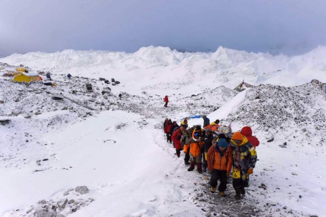An injured person is carried by rescue members to be airlifted by rescue helicopter at Everest Base Camp on April 26, 2015, a day after an avalanche triggered by an earthquake devastated the camp. Rescuers in Nepal are searching frantically for survivors of a huge quake on April 25, that killed nearly 2,000, digging through rubble in the devastated capital Kathmandu and airlifting victims of an avalanche at Everest base Camp. The bodies of those who perished lie under orange tents. AFP PHOTO/ROBERTO SCHMIDTROBERTO SCHMIDT/AFP/Getty Images