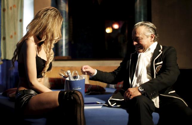 Owner Hermann "Pascha" Mueller sits next to a woman in his nightclub in Salzburg, Austria, June 16, 2015. The nightclub is offering customers free sex in a summer-long protest over what its owner sees as punitive tax payments.  REUTERS/Leonhard Foeger