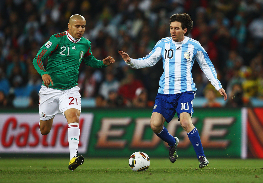 JOHANNESBURG, SOUTH AFRICA - JUNE 27: Lionel Messi of Argentina is challenged by Adolfo Bautista of Mexico during the 2010 FIFA World Cup South Africa Round of Sixteen match between Argentina and Mexico at Soccer City Stadium on June 27, 2010 in Johannesburg, South Africa. (Photo by Quinn Rooney - FIFA/FIFA via Getty Images)