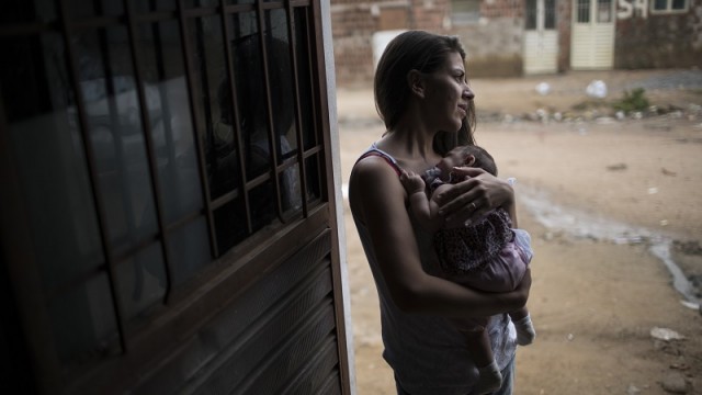 In this Dec. 22, 2015 photo, Angelica Pereira holds Luiza outside their house in Santa Cruz do Capibaribe, Pernambuco state, Brazil. Luiza was born in October with a rare condition, known as microcephaly. The Zika virus, first detected in humans about 40 years ago in Uganda, has long seen as a less-painful cousin to dengue and chikunguya, which are spread by the same Aedes mosquito. Until a few months ago, investigators had no reported evidence it might be related to microcephaly. (AP Photo/Felipe Dana)