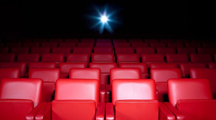 Sala de cine vacía con asientos rojos.