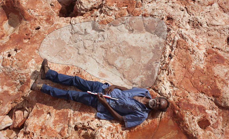 Hombre posando junto a la huella de dinosaurio más grande de la que se tenga registro
