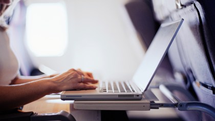 Woman typing on a laptop computer in a commercial airplane.