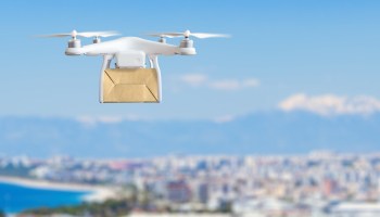 Dron sobrevolando ciudad con paquete