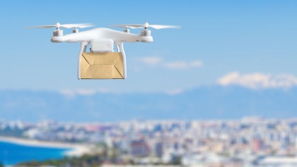 Dron sobrevolando ciudad con paquete
