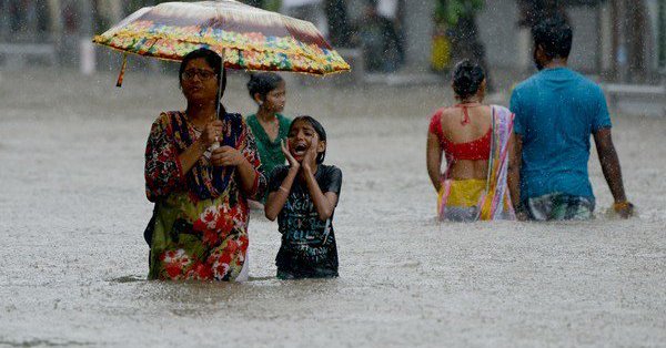 personas caminando con el agua a la altura de la cadera por la inundaciones en India