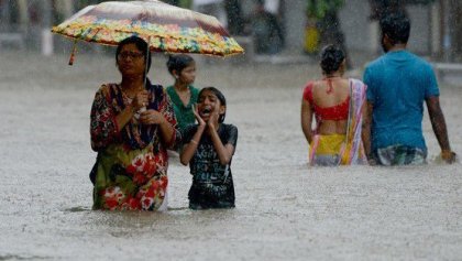 personas caminando con el agua a la altura de la cadera por la inundaciones en India