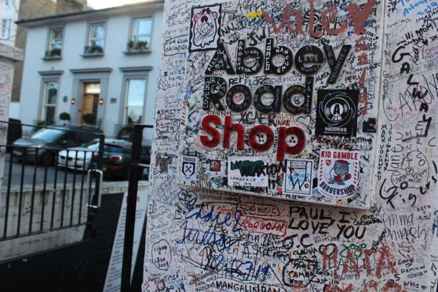 Entre las calles de Camdem y Westminster, se encuentra el crucero más famoso de todo el mundo, millones de personas viajan anualmente a Londres solo para tomarse la foto del recuerdo en el paso de cebra de Abbey Road. No obstante, una vez estando allí cualquiera puede notar que la época de los Beatles fue hace mucho, mucho tiempo. Pero gracias al confinamiento por el COVID-19, la avenida pudo recibir una ‘manita de gato’. Han pasado 50 años desde el día en que los Beatles inmortalizaron el crucero para la portada de Abbey Road, de cierta forma, no ha pasado tanto tiempo, sin embargo, entre los grafitis, el pasar de los miles de turistas y la falta de mantenimiento y el descuido vecinal, lejos de ser un sitio turístico, parecía el set de una película de terror. Lo que muy poca gente sabe, es que en realidad la calle donde se grabaron canciones clásicas como "Something", "Here Comes the Sun" y "Why", es una calle transitada por ambos sentidos y si encima le contamos que diariamente cientos de personas se paran en medio para tratar de lograr la fotografía perfecta entre alto y alto, es casi imposible arreglarla, no obstante, la pandemia por COVID-19, también ha traído sus cosas buenas. Cuando el primer ministro británico, Boris Johnson, ordenó a los ciudadanos permanecer en el interior de sus casas, los equipos urbanos aprovecharon para hacer planes para la restauración de la calle. “Este paso de cebra en Londres no es un castillo o una catedral, pero, gracias a los Beatles y una sesión de fotos de 10 minutos una mañana de agosto de 1969, tiene un reclamo tan fuerte como cualquier otro como parte de nuestro patrimonio", dijo John Penrose, Ministro de Turismo y Patrimonio para un diario local. Un grupo de trabajadores, emprendieron las obras de mantenimiento, reforzaron tanto las líneas del cruce como el letrero fijado justo debajo de las aceras y donde se puede leer “Voltea para ambos lados” [antes de cruzar]. También, pintaron en zig-zag la línea de división de los sentidos para los conductores. Aunque ahora, los trabajos de remodelación contrastan con el cada vez más grafiado estudio, que se llena de tinta cada vez que algún turista piensa que es lindo escribir el típico “Yo estuve aquí. Pero eso sí, si algún día te decides a visitar Abbey Road, no te conformes con la foto de tu cámara. Las cámaras de seguridad graban todo lo que pasa en el famoso crucero las 24 horas del día y lo mejor, es que puedes consultar tu visita con tan solo introducir el día y la hora en la que fuiste en el portal de EathCam 