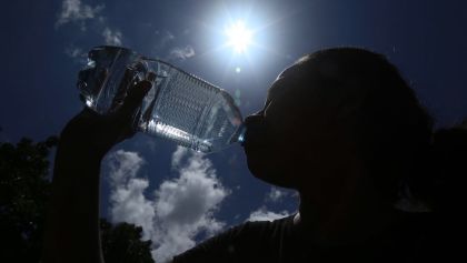 Una mujer tomando agua bajo el rayo del sol
