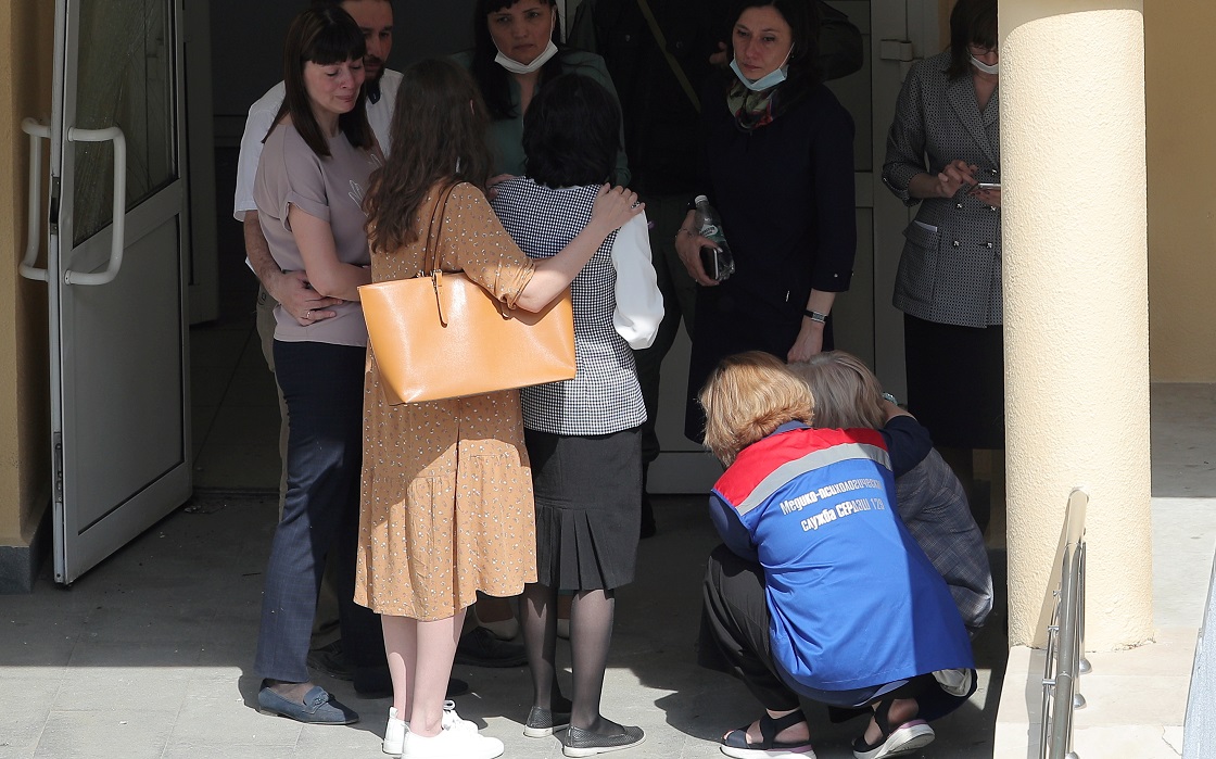 KAZAN, RUSSIA  MAY 11, 2021: A medical worker comforts relatives of students of school No 175 where two attackers opened fire; at least one teacher and eight students are reported dead. 