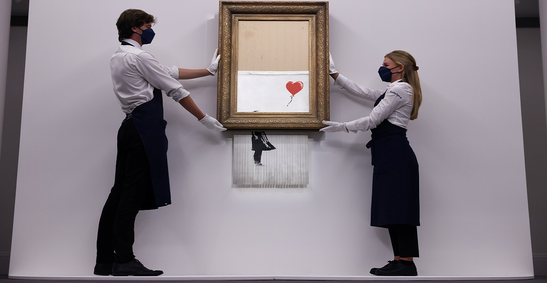 FILE PHOTO: A gallery assistant poses by 'Love is in the Bin', an artwork by Banksy, which will be for sale in an auction, at Sotheby's in London, Britain, September 3, 2021.