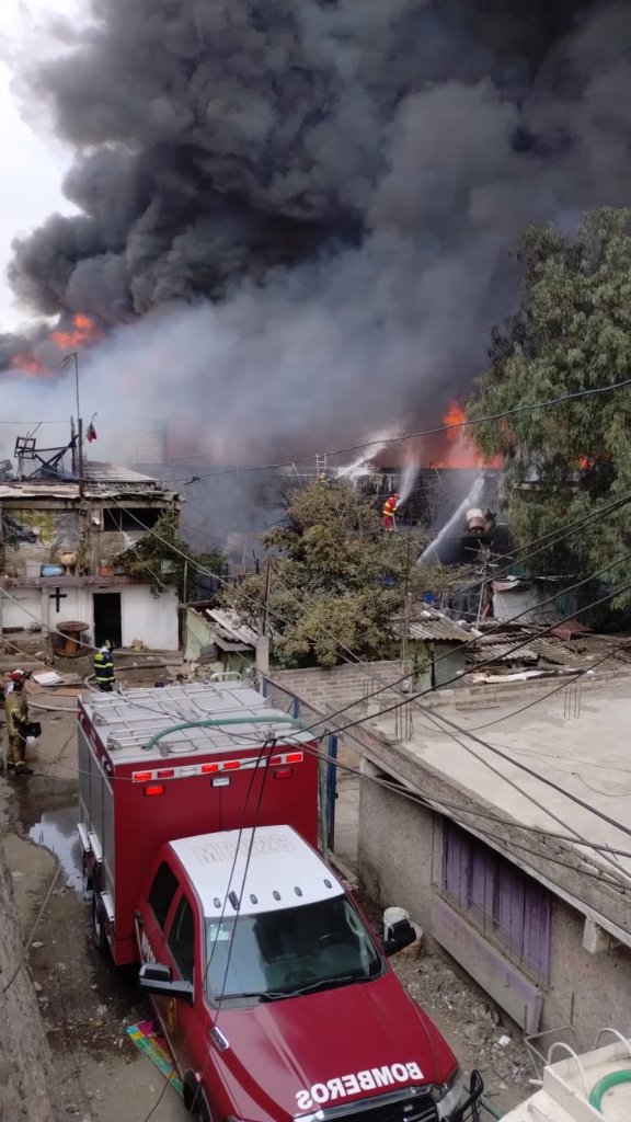 Bomberos luchan desde casas vecinas para apagar el fuego en una recicladora de PET de Valle de Chalco. 