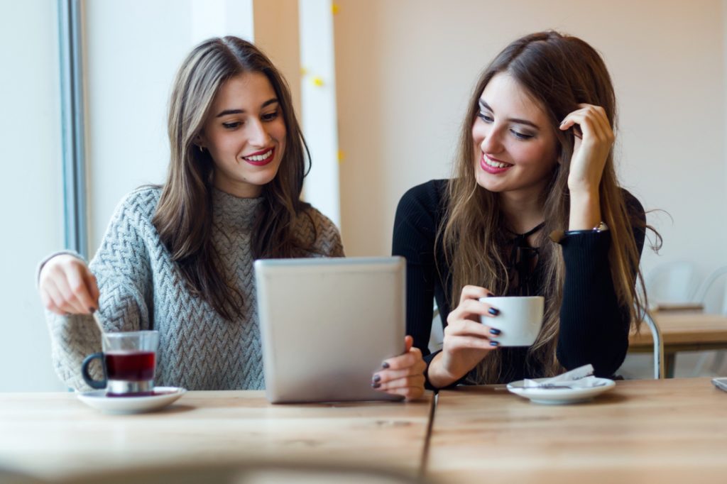 mujeres tomando cafe viendo tablet