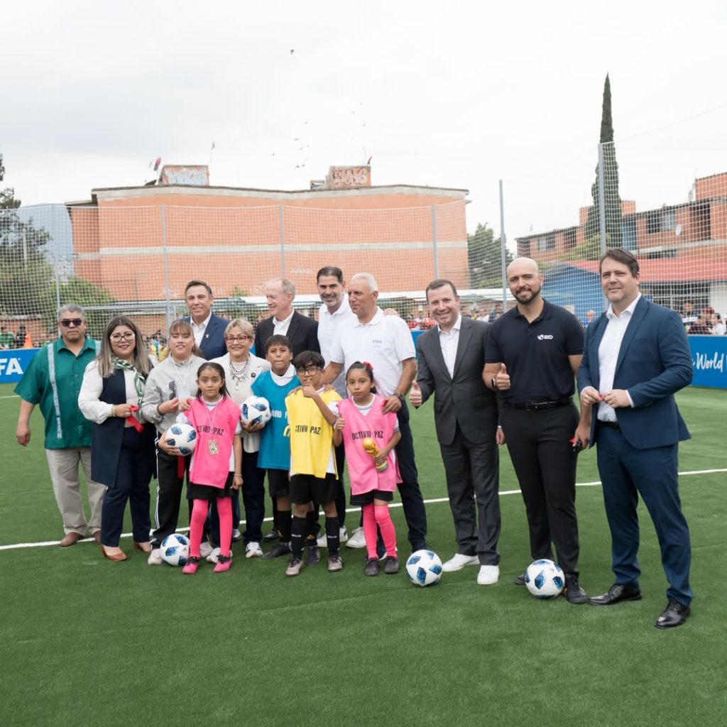 Niñas, niños y representantes de FIFA y el BID posan en una cancha del programa FIFA Arena en México