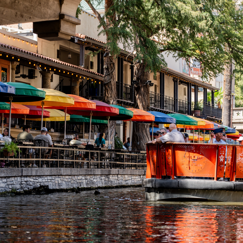 Turistas disfrutando de los restaurantes y botes a la orilla del River Walk en San Antonio, Texas.