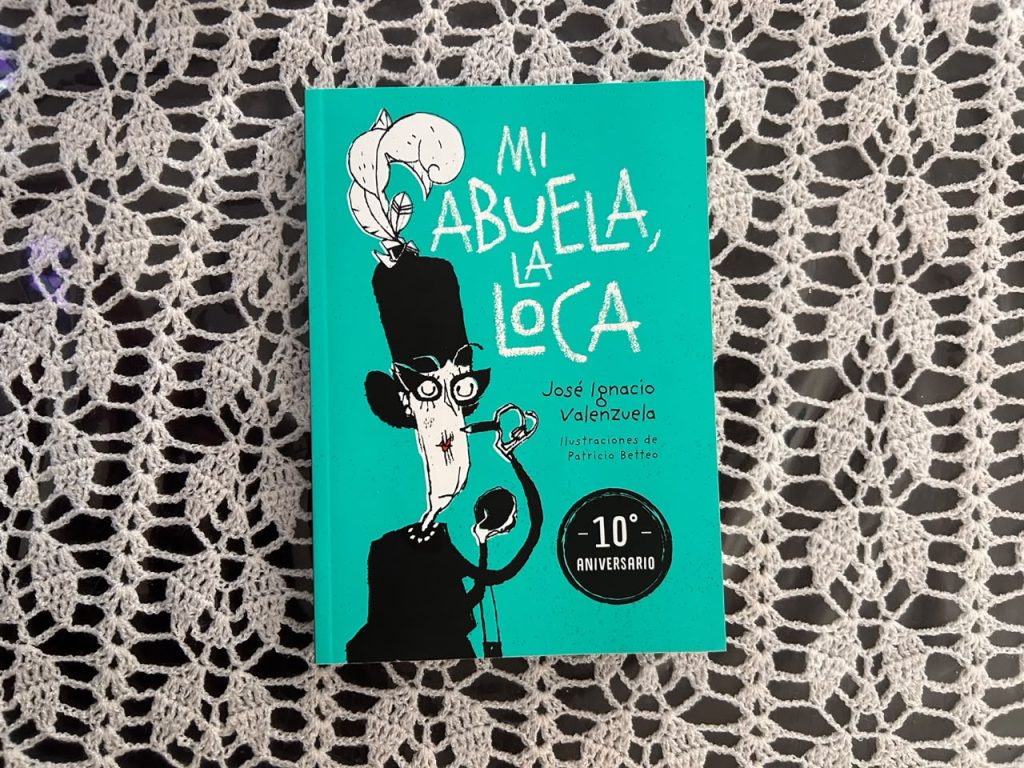 Portada del libro "Mi abuela la loca" de José Ignacio Valenzuela con sello de 10 aniversario, sobre un fondo de encaje blanco.