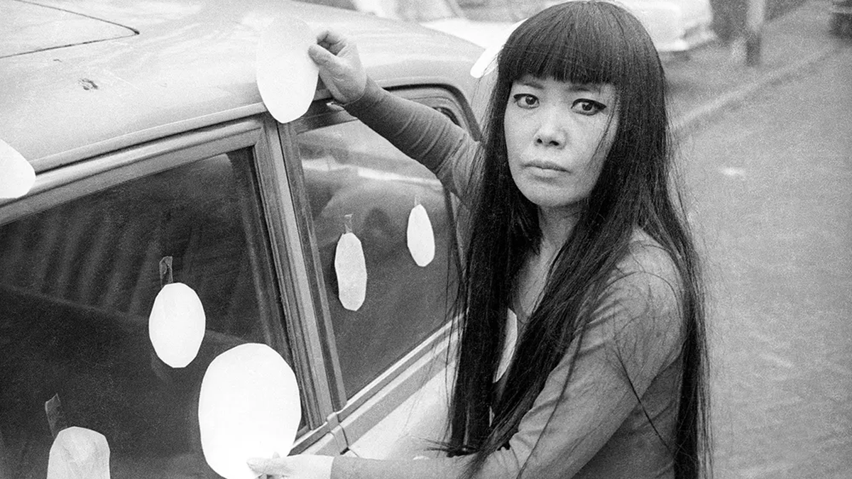Yayoi Kusama pegando lunares en la ventana de su vehículo conocido como Dot Car en 1965.