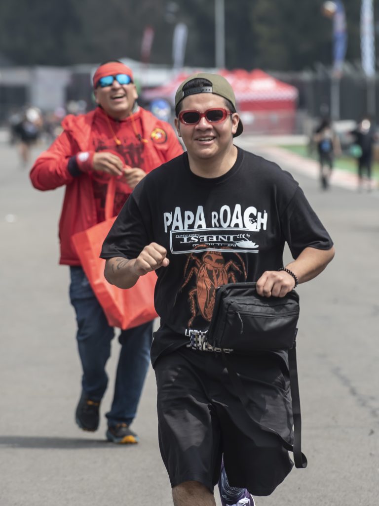Asistente vistiendo playera de Papa Roach caminando sonriente por el festival Vans Warped Tour México 2026.