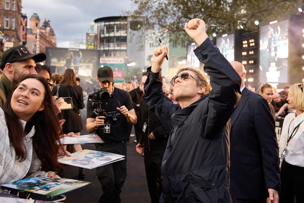 Fotografía de Liam Gallagher celebrando y alzando los brazos con un marcador en la mano frente a los fans, durante la premiere en el Reino Unido del documental 'Oasis: Don't Look Back in Anger'.