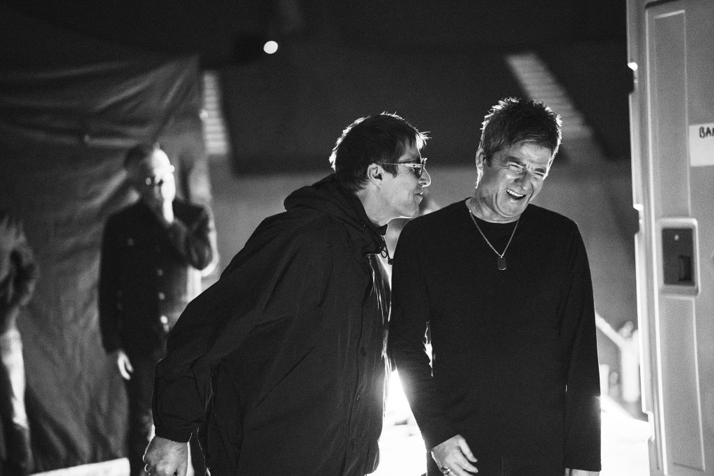 Fotografía en blanco y negro de Liam y Noel Gallagher riendo juntos, en una escena del documental de Oasis, Don't Look Back in Anger.
