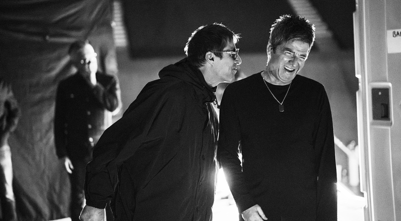 Fotografía en blanco y negro de Liam y Noel Gallagher sonriendo juntos en el documental 'Don't Look Back in Anger'.