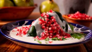Chile en nogada tradicional cubierto con salsa de nuez, granada y perejil