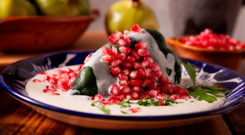 Chile en nogada tradicional cubierto con salsa de nuez, granada y perejil