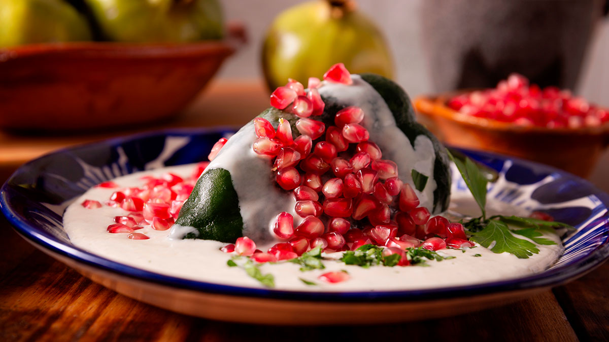 Chile en nogada tradicional cubierto con salsa de nuez, granada y perejil